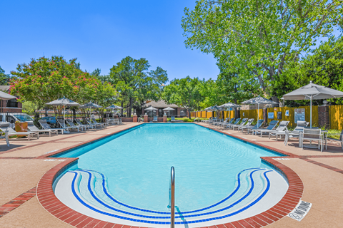 a resort style pool with lounge chairs and umbrellas